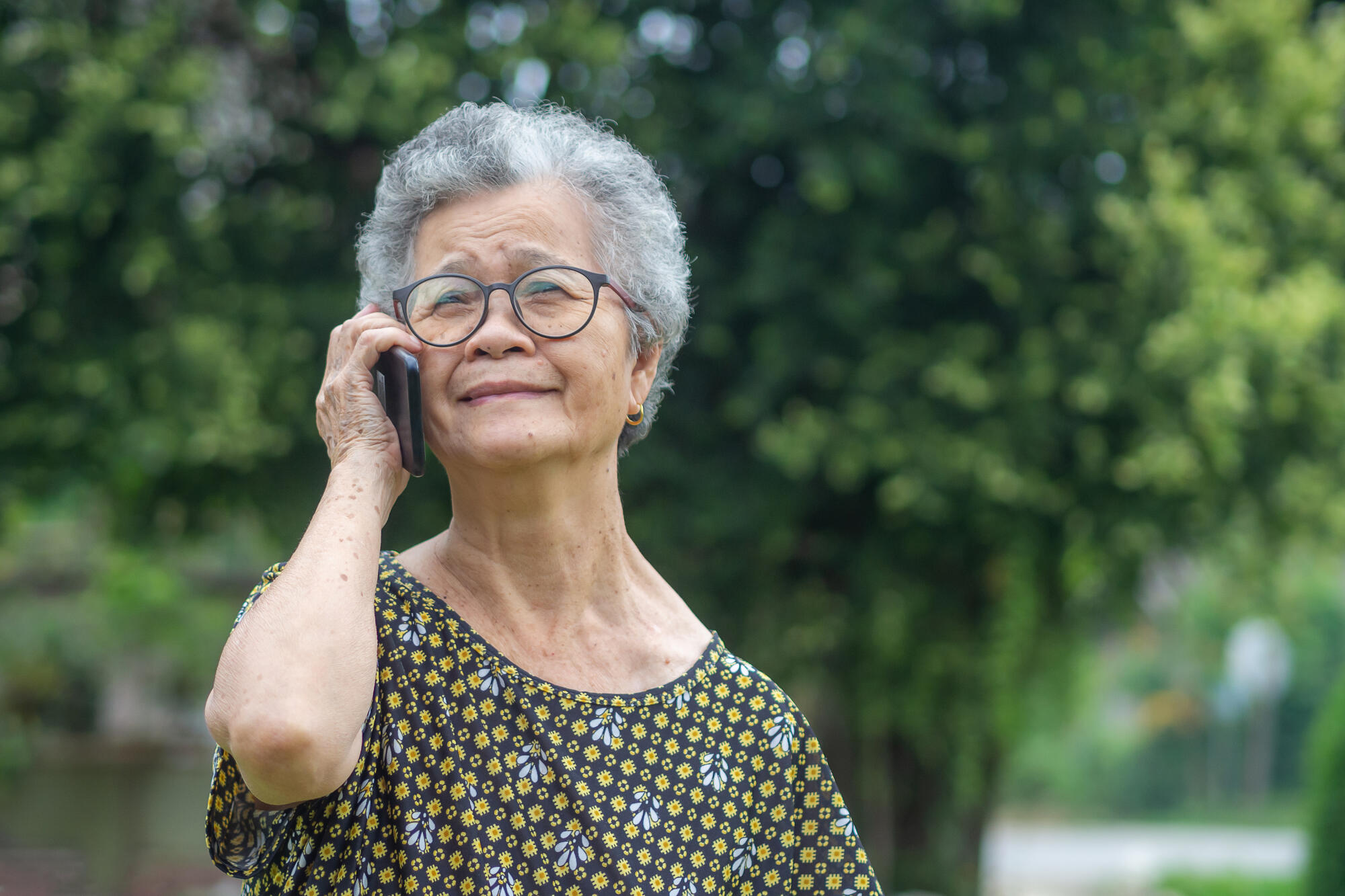 Happy beautiful senior woman is using a smartphone and looking u Happy beautiful senior woman is using a smartphone and looking u