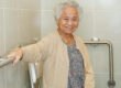 Asian elderly old woman patient use toilet support rail in bathr