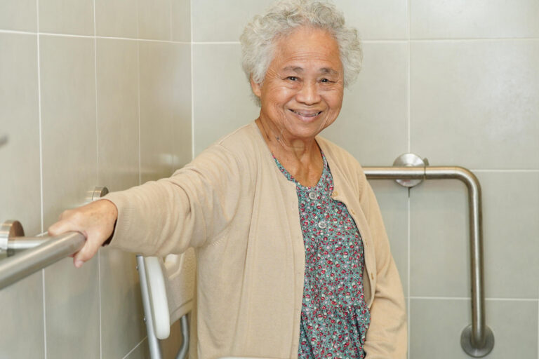 Asian elderly old woman patient use toilet support rail in bathr Asian elderly old woman patient use toilet support rail in bathr