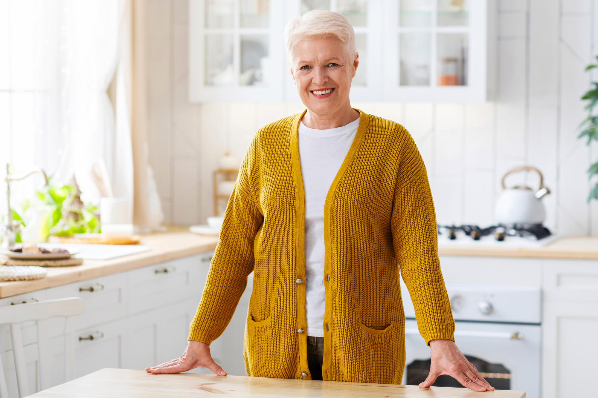 Happy senior lady posing in kitchen at home Happy senior lady posing in kitchen at home
