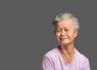 An elderly Asian woman looking at the camera with a smile while