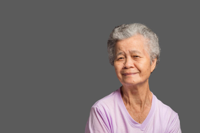 An elderly Asian woman looking at the camera with a smile while