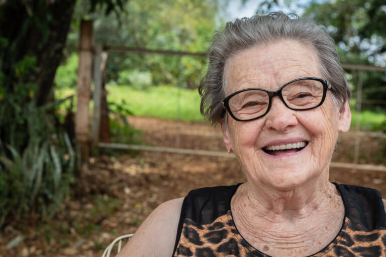 Senior happy old farmer woman with eyeglasses smiling and looking at camera