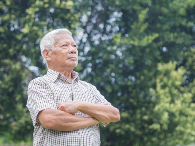 Portrait of an elderly Asian man with short gray hair smiling an