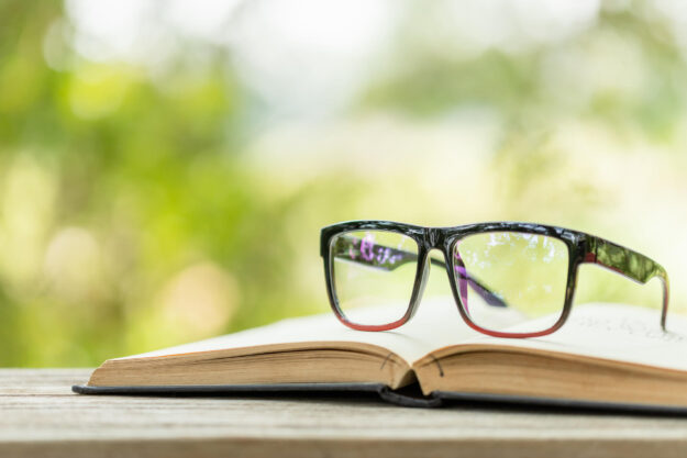 Book and eye glasses on wooden table with abstract green nature Book and eye glasses on wooden table with abstract green nature