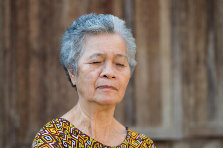 Senior woman with short gray hair, looking down and the face of