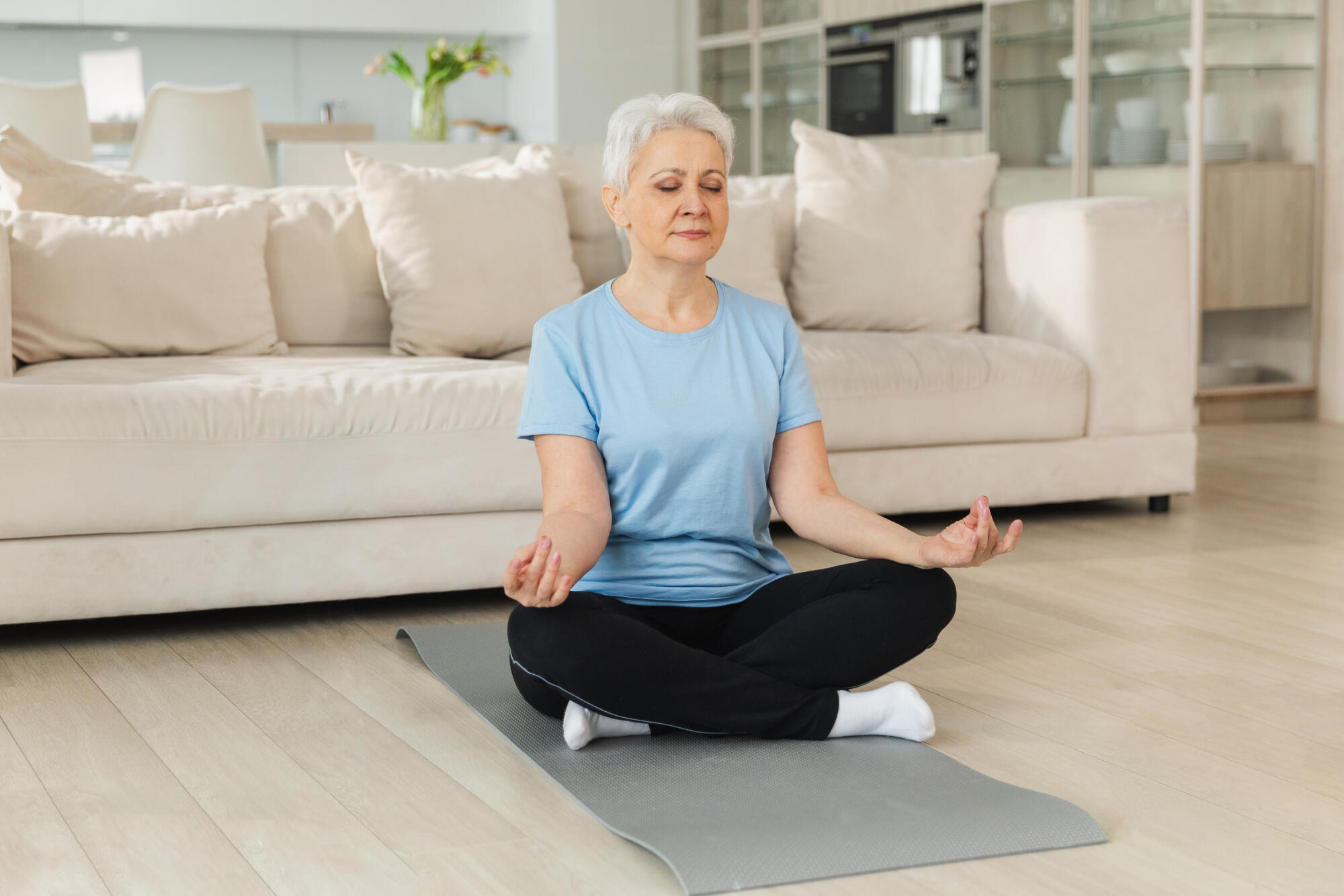 Yoga mindfulness meditation. Senior adult mature woman practicing yoga at home. Mid age old lady sitting in lotus pose on yoga mat meditating relaxing, Older middle aged woman doing breathing practice Yoga mindfulness meditation. Senior adult mature woman practicing yoga at home. Mid age old lady sitting in lotus pose on yoga mat meditating relaxing, Older middle aged woman doing breathing practice