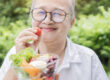 Happy Asian retirement women holding a tomato with fresh salad b