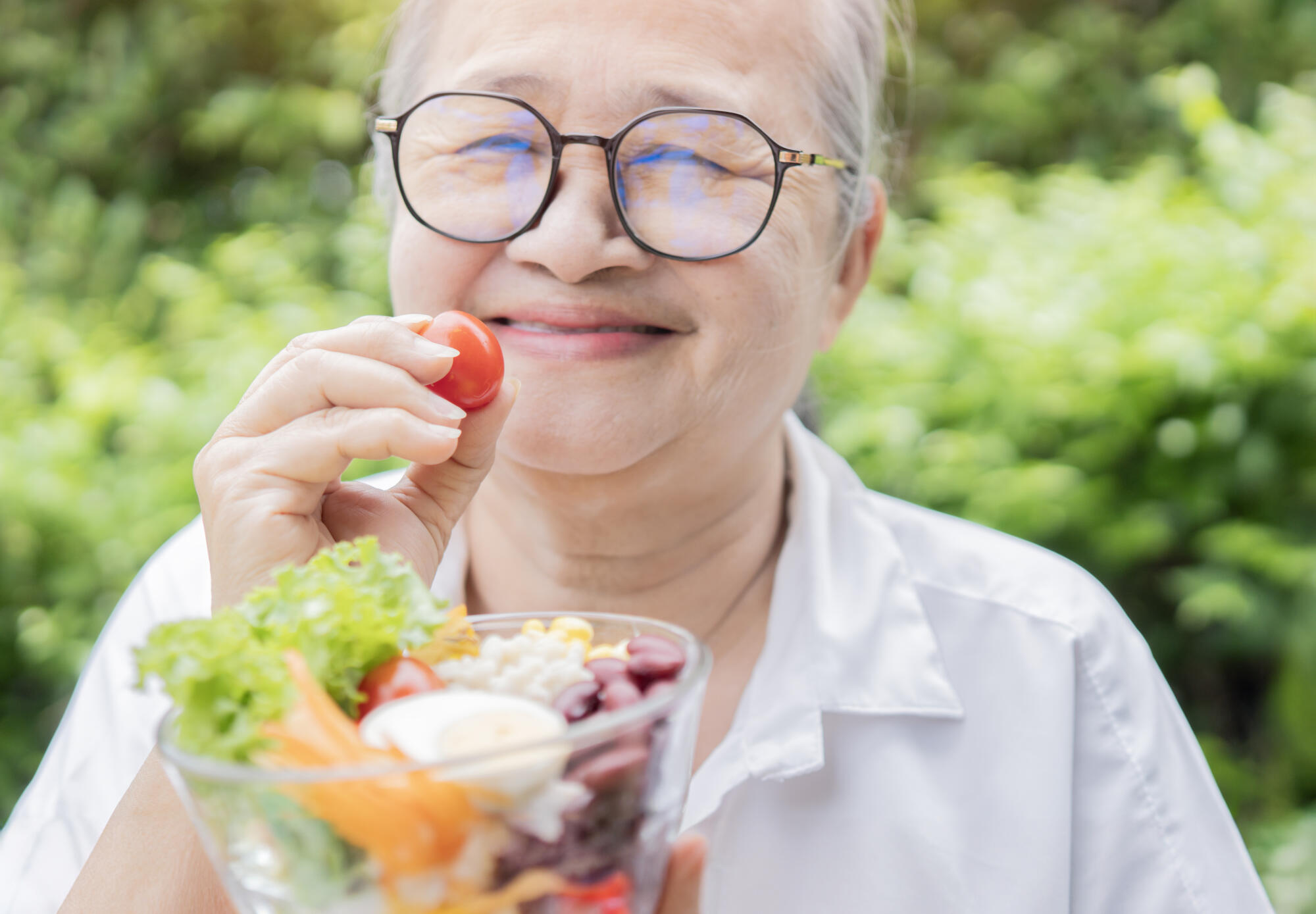 Happy Asian retirement women holding a tomato with fresh salad b Happy Asian retirement women holding a tomato with fresh salad b