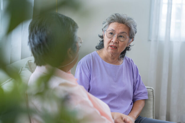Two happy cheerful elderly aged female friends relaxing together