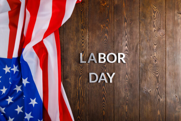 words labor day laid with silver metal letters on wooden surface with crumpled USA flag on left side words labor day laid with silver metal letters on wooden surface with crumpled USA flag on left side