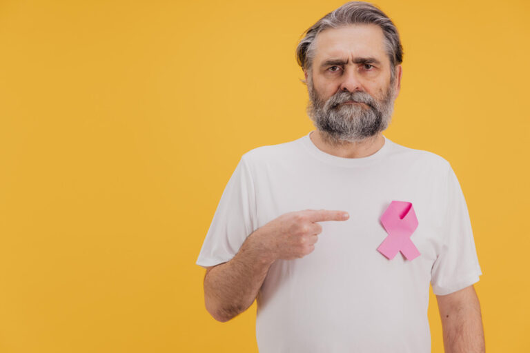 Senior Man Showing Pink Ribbon for Breast Cancer Awareness on Yellow Background Senior Man Showing Pink Ribbon for Breast Cancer Awareness on Yellow Background