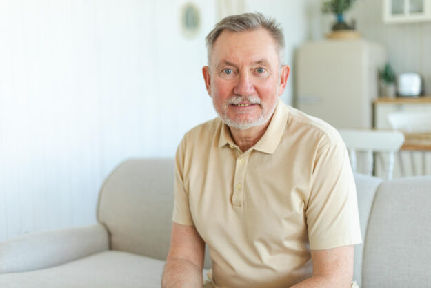 Confident stylish middle aged senior man at home. Older mature 70s man smiling. Happy attractive senior beard grandfather looking camera close up face headshot portrait. Happy people.