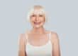 Natural beauty. Beautiful senior woman looking at camera and smiling while standing against grey background