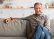Contented Senior Man Sitting On Sofa Relaxing At Home