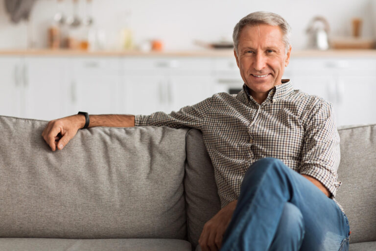 Contented Senior Man Sitting On Sofa Relaxing At Home