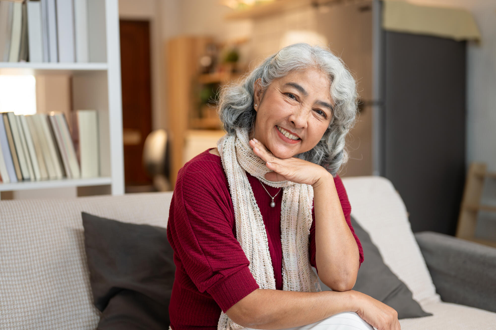 A portrait of a happy, healthy retired Asian woman at home, sitting on a sofa. A portrait of a happy, healthy retired Asian woman at home, sitting on a sofa.