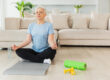 Yoga mindfulness meditation. Senior adult mature woman practicing yoga at home. Mid age old lady sitting in lotus pose on yoga mat meditating relaxing, Older middle aged woman doing breathing practice