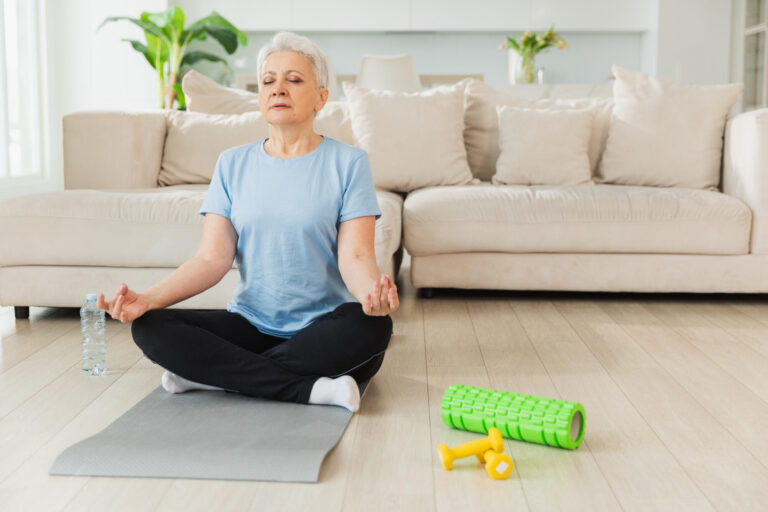 Yoga mindfulness meditation. Senior adult mature woman practicing yoga at home. Mid age old lady sitting in lotus pose on yoga mat meditating relaxing, Older middle aged woman doing breathing practice