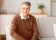 Smiling Senior Gentleman Sitting On Couch At Home