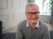 Portrait of confident stylish European middle aged senior man at home. Older mature 70s man smiling. Happy attractive senior grandfather looking camera close up face headshot portrait. Happy people.