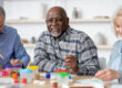 Happy senior black man enjoying painting activity with his friends