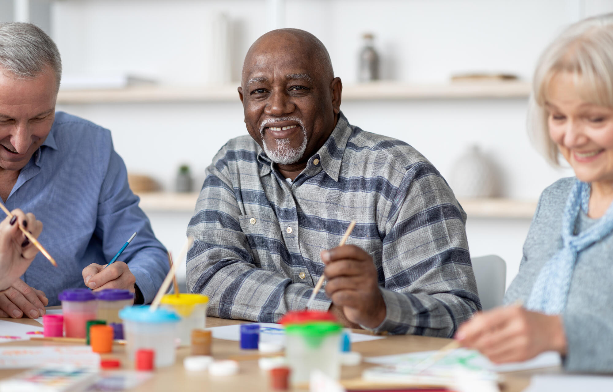 Happy senior black man enjoying painting activity with his friends Happy senior black man enjoying painting activity with his friends