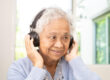 Asian senior woman listen to music with headphone smile and enjo