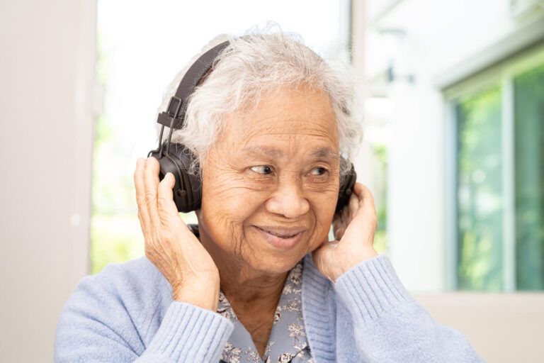 Asian senior woman listen to music with headphone smile and enjo