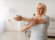 Mature woman exercising at home stretching arm