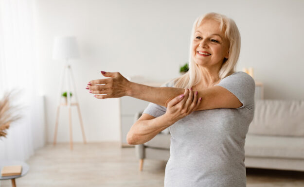 Mature woman exercising at home stretching arm