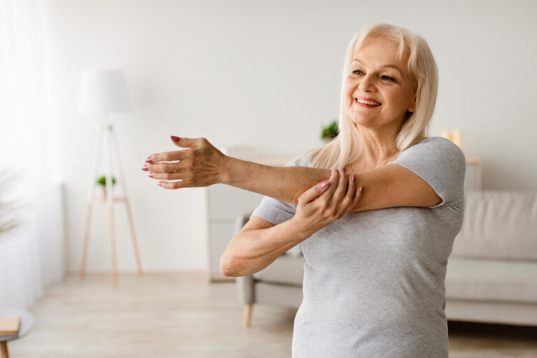 Mature woman exercising at home stretching arm