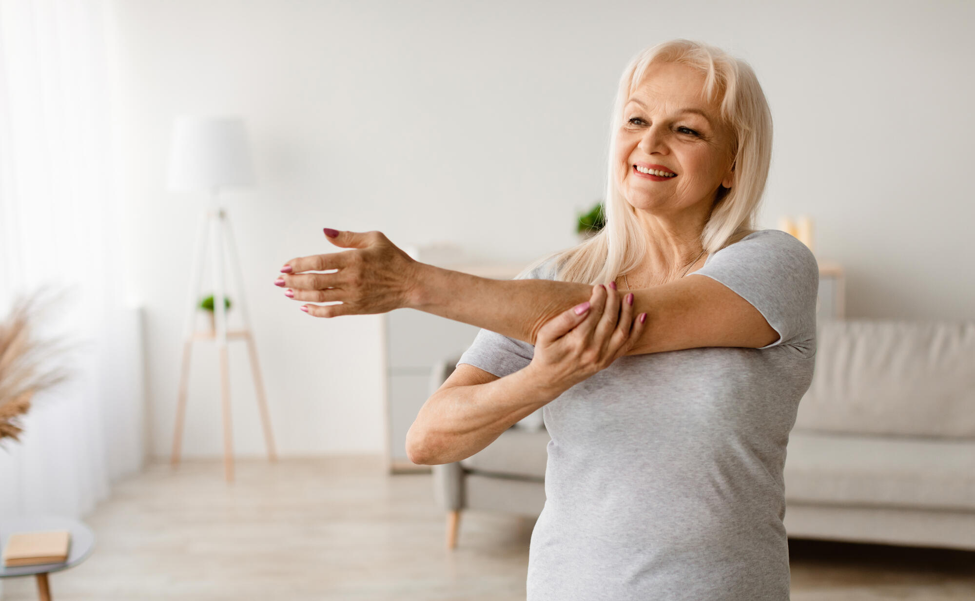 Mature woman exercising at home stretching arm Mature woman exercising at home stretching arm