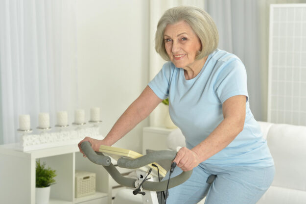 Elderly woman exercising on an exercise bike Elderly woman exercising on an exercise bike