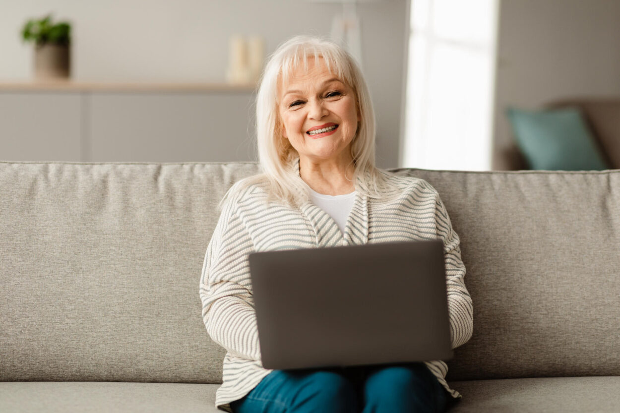 Mature woman sitting on couch and using computer