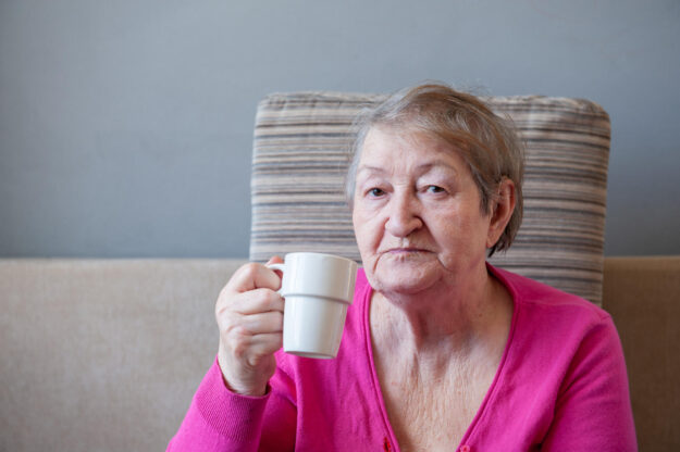 Seriously,Ill,Elderly,Woman,In,Pink,Blouse,Is,Sitting,On