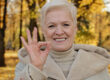 Happy elderly woman joyfully smiling standing in autumn park mature grandmother looking at camera showing gesture okay symbol of satisfaction everything fine positive cheerful senior retired outdoors
