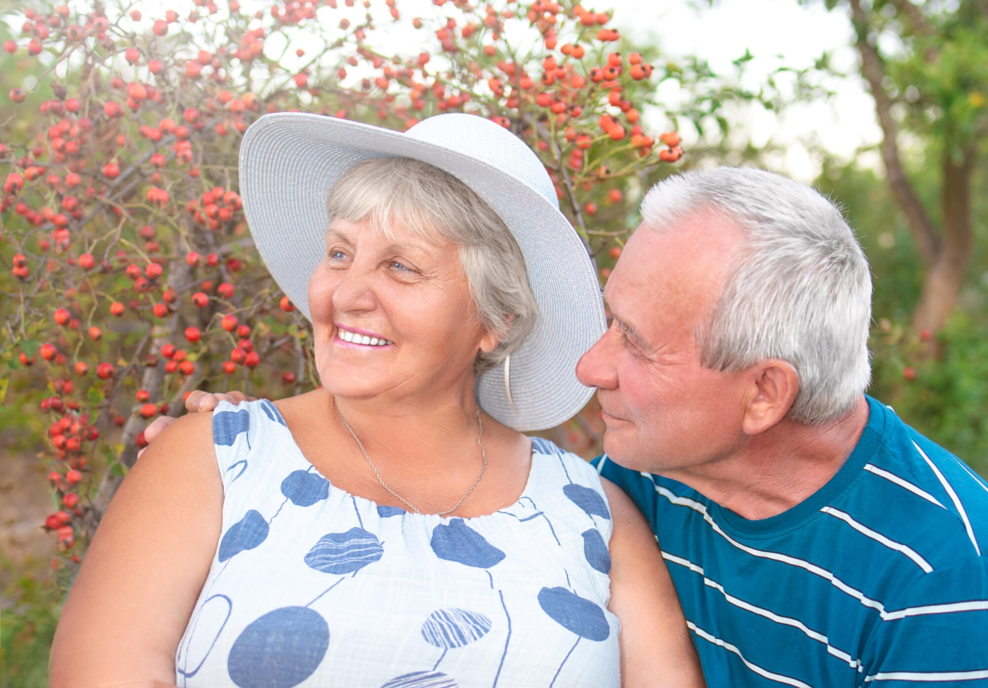 Authentic outdoor shot of aging couple having fun in the garden and blessed with love. During their game man is trying to kiss his wife and she is laughing out loud. Love and family concept.