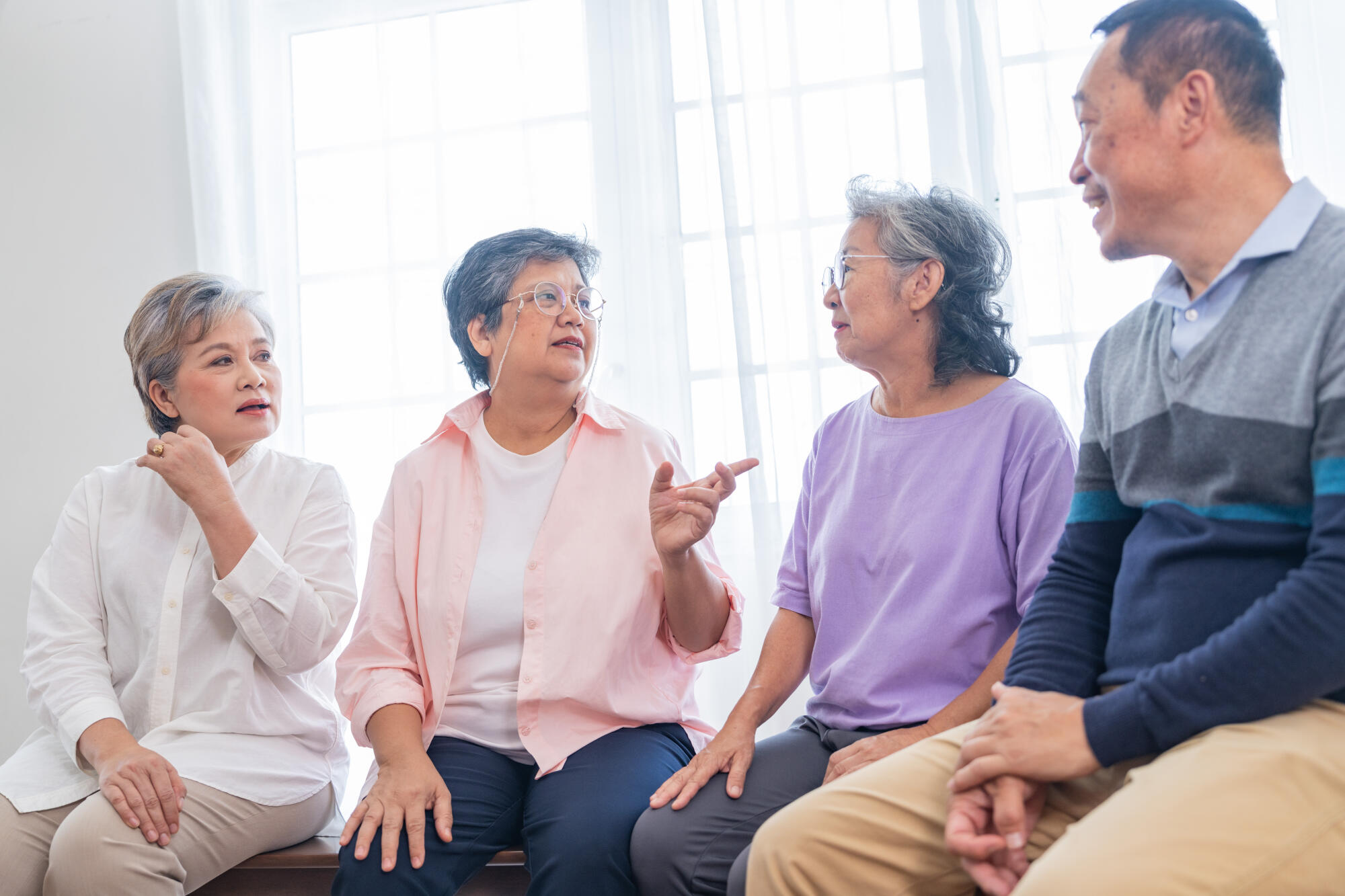 senior females and male sitting on bench. older people are liste