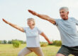Active senior couple doing the warrior pose in a field, showing