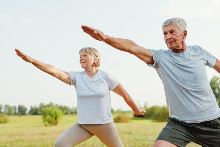 Active senior couple doing the warrior pose in a field, showing Active senior couple doing the warrior pose in a field, showing