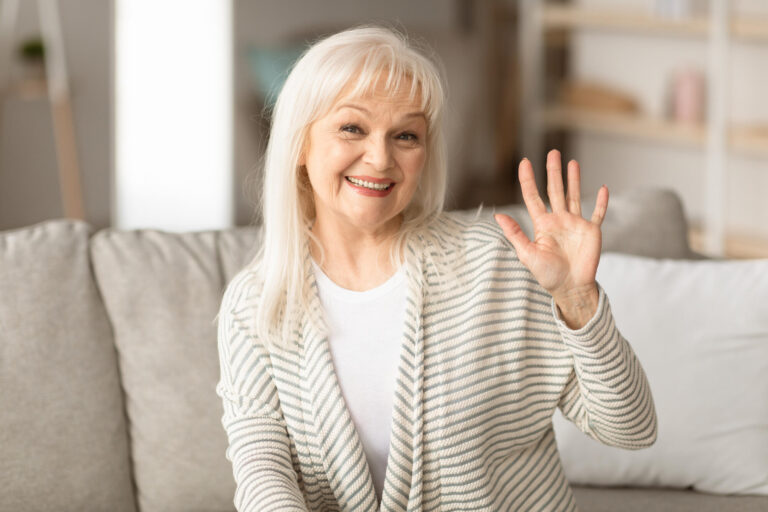 Mature woman waving at camera and smiling Mature woman waving at camera and smiling