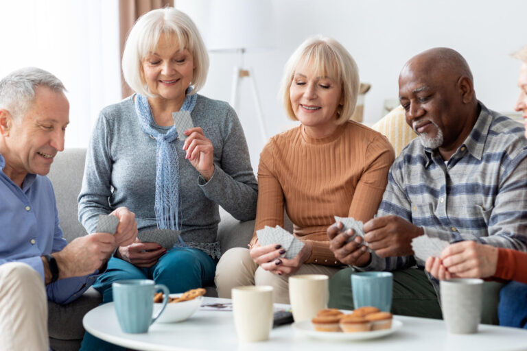 Happy senior people playing cards at nursing home