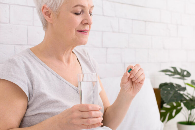 Senior Woman Taking Medication With a Glass of Water Indoors