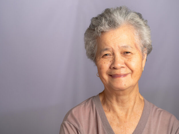 Portrait of an elderly Asian woman with short gray hair looking