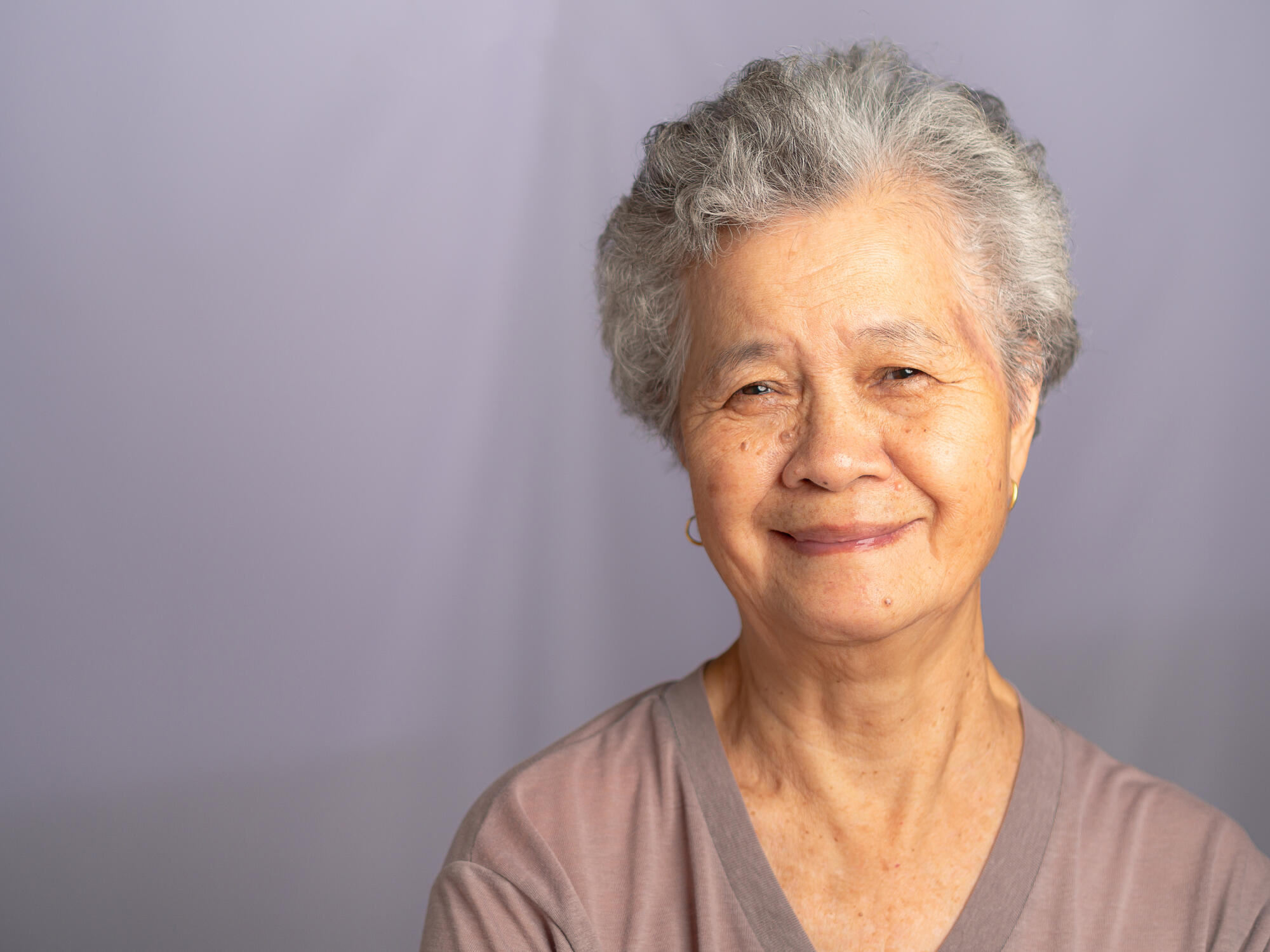 Portrait of an elderly Asian woman with short gray hair looking