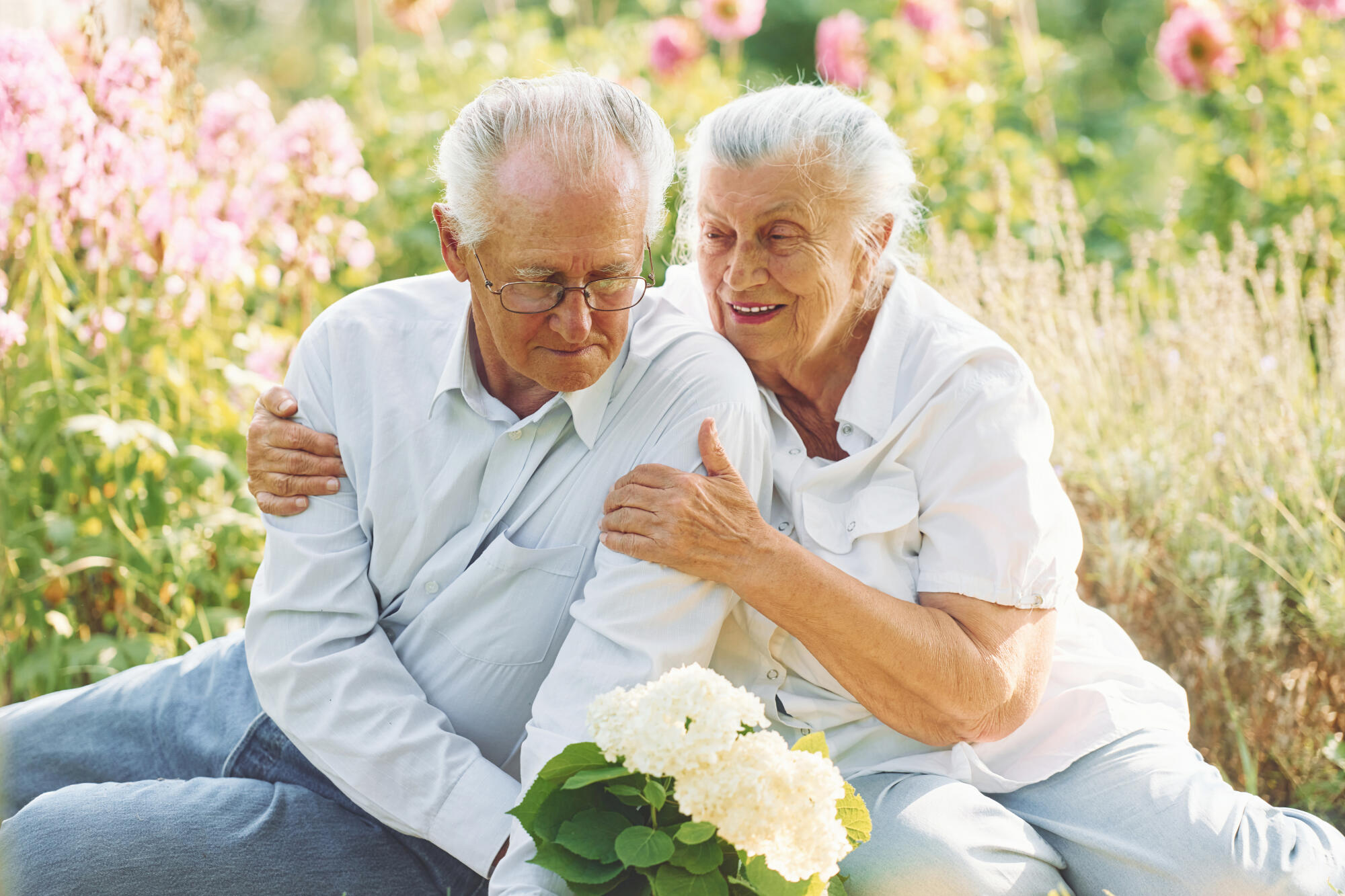 Sitting on the ground. Lovely senior couple is in the garden together Sitting on the ground. Lovely senior couple is in the garden together