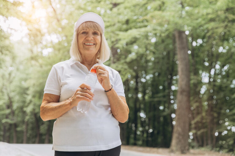 Portrait of a happy active beautiful senior woman holding a bott