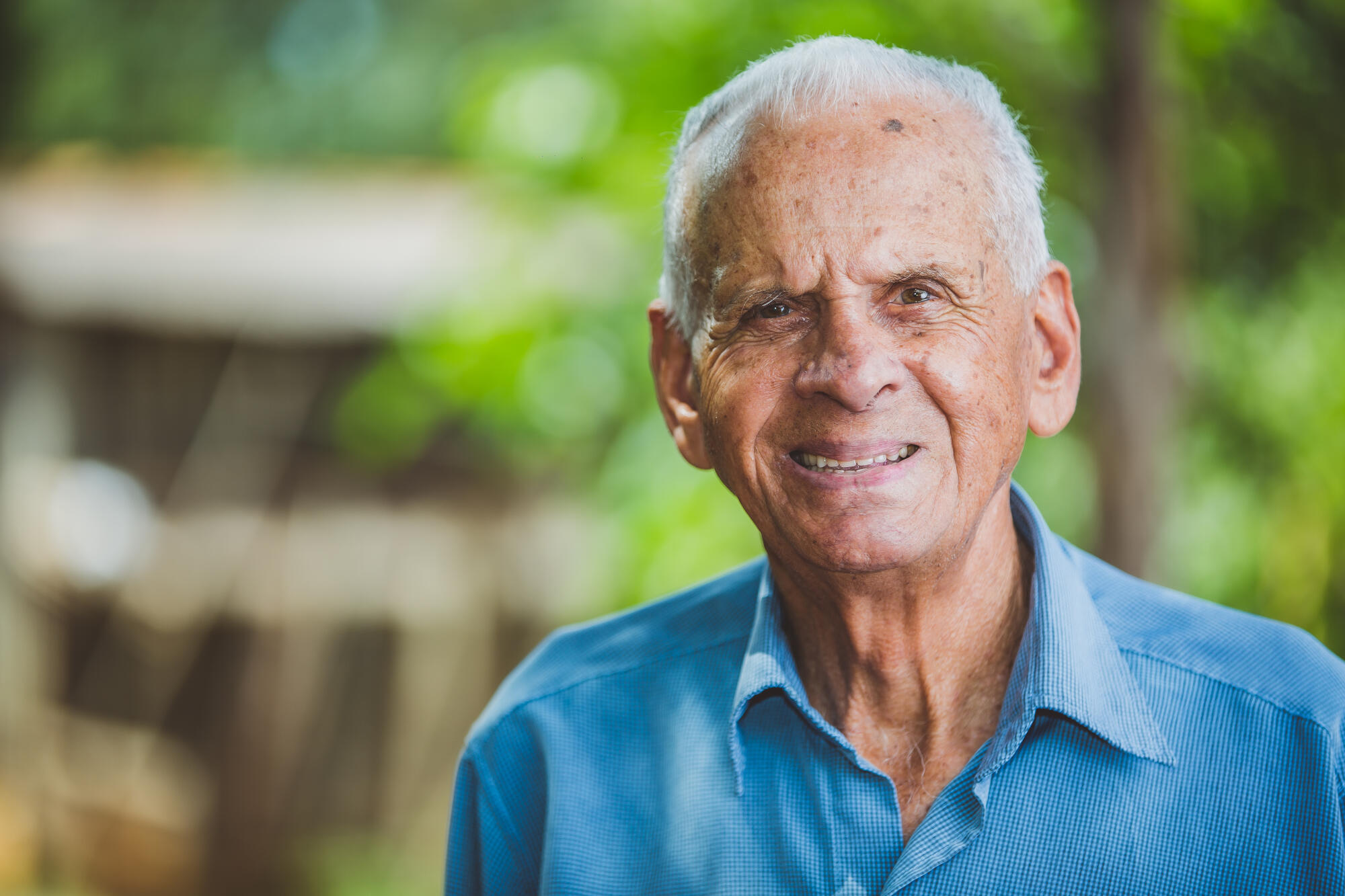 Portrait of smiling beautiful older male farmer. Elderly man at farm in summer day. Gardening activity. Brazilian elderly man.